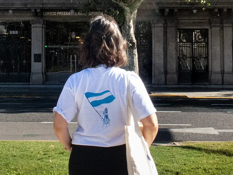 Persona de espaldas con una remera blanca estampada con una bandera argentina dibujada a mano